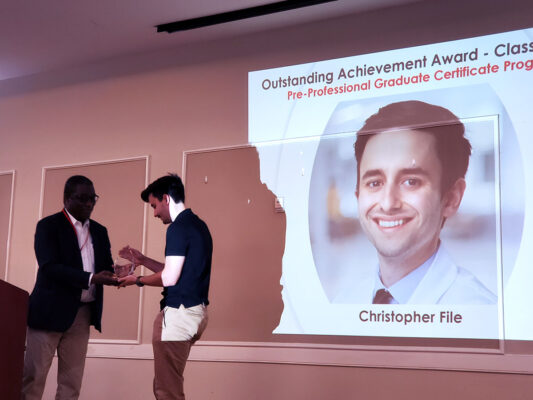 Christopher File receives the program's first Outstanding Student Award from Program Co-Director, Dr. Oyajobi
