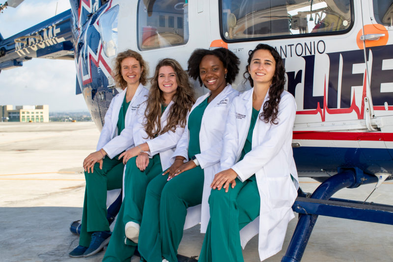 Four female doctors sitting on a helicopter skid