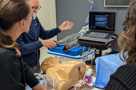 Doctors using ultrasound machine to intubate manakin.