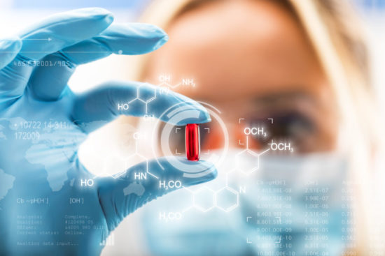 Female Scientist looking at medical pill
