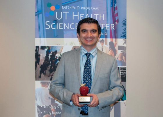 Dr. Seifi smiling with his Apple-shaped Best Teacher Award.