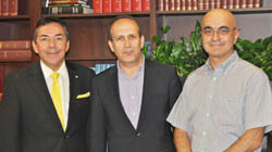 Turkish Ambassador Namik Tan standing and smiling with Drs. David Jimenez and Murat Digicaylioglu in the neurosurgery conference room.