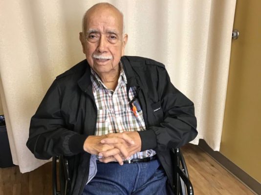 Patient Frank Ibarra sitting in a wheelchair and smiling during a clinic visit.