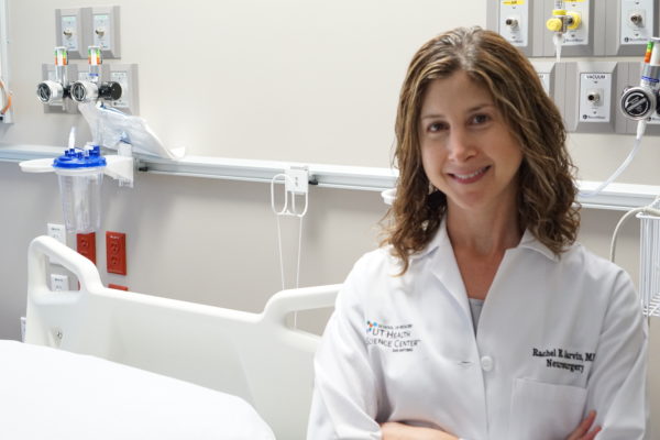 Dr. Rachel Garvin smiling and standing next to a hospital bed.