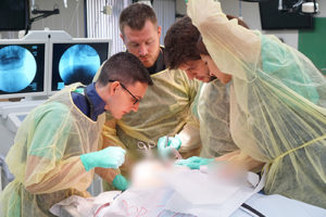 People standing around a cadaver with medical instruments.