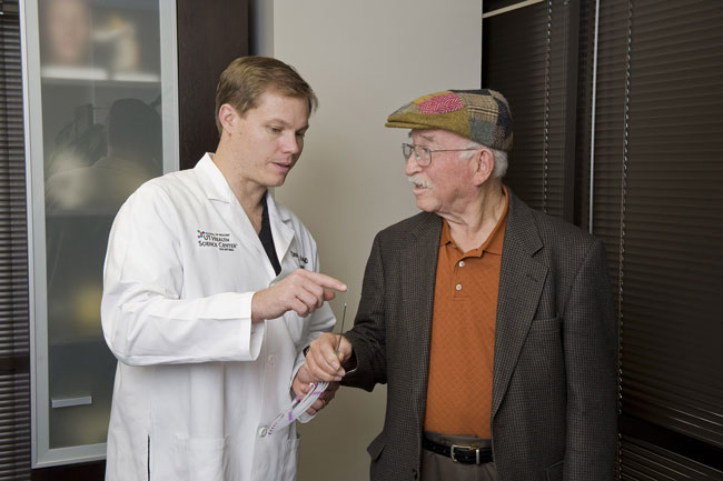 Dr. Koebbe using a piece of equipment to explain something to Patient Lino Ozuna.