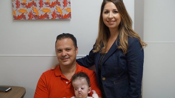 Pablo and Amanda Gonzalez smiling with their daughter, Alessia, in clinic.