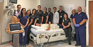The neurocritical care team smiling for a group photo while they learn how to place invasive central lines.