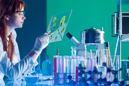 A woman in a white coat studying something in a lab.