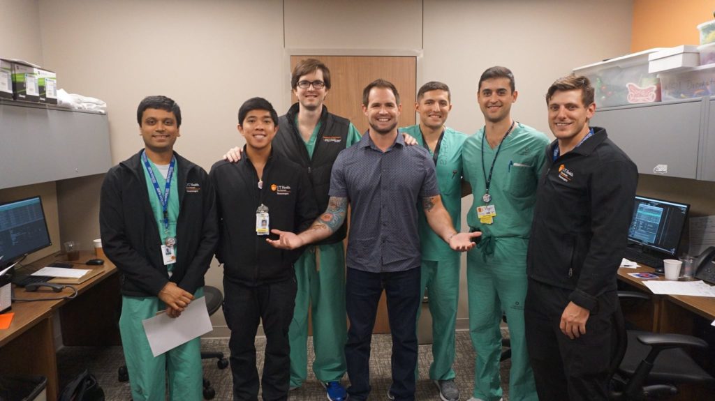 Former Patient James Durham standing and smiling with a group of Neurocritical Care Team members.