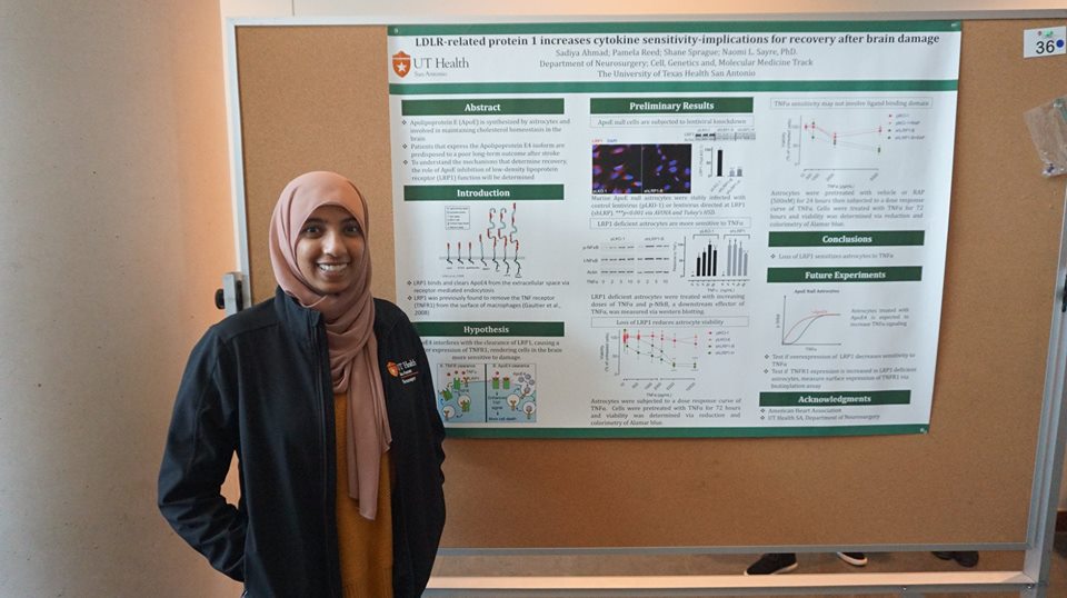 Sadiya Ahmad standing in front of her research poster and smiling.