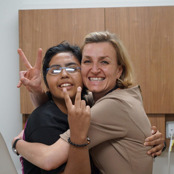 Dr. Izabela Tarasiewicz and Ashlyn smiling during and clinic visit while they both throw peace signs at the camera.