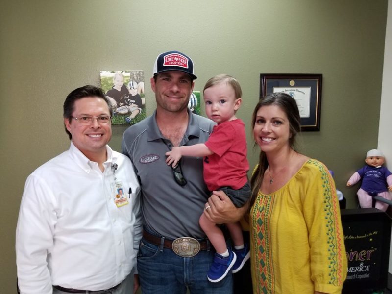 Cranial Remolding Clinical Director Darren Poidevin smiling while standing next to Patient Hudson Lockhart and his parents.