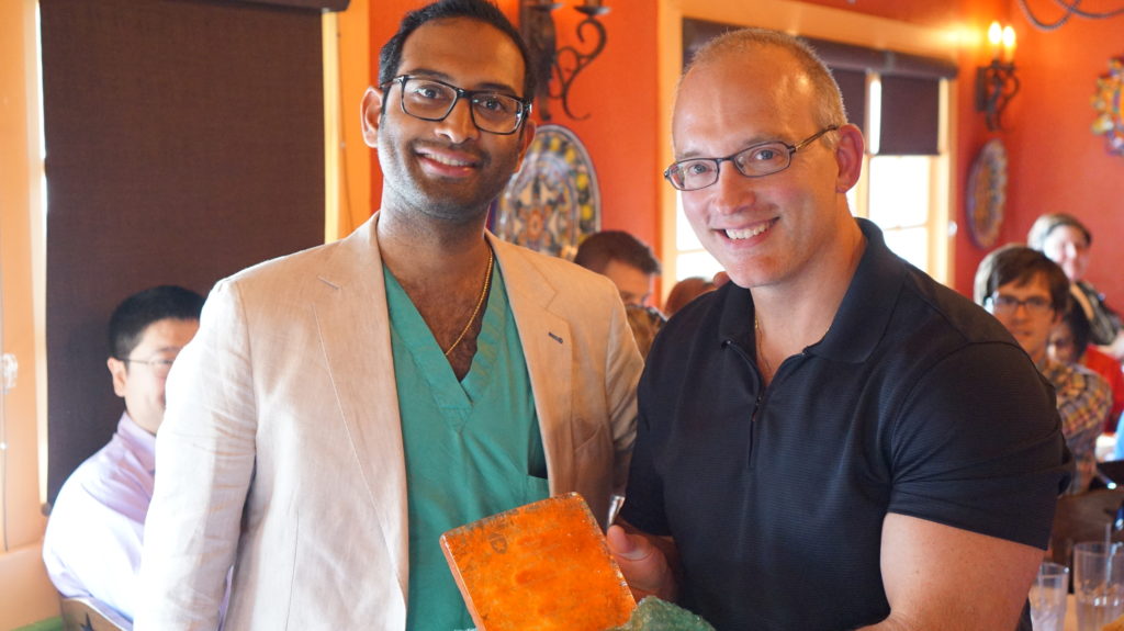 Dr. Floyd smiling while presenting Dr. Grandhi with his farewell gift.