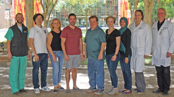 The Department of Neurosurgery’s laboratory staff standing outside and smiling in front of the colorful Academic Learning and Teaching Center.