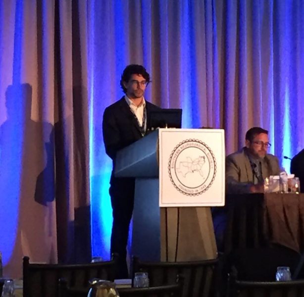Dr. David Wallace standing before a podium and presenting his research at Neurosurgical Society meeting in Key Largo.