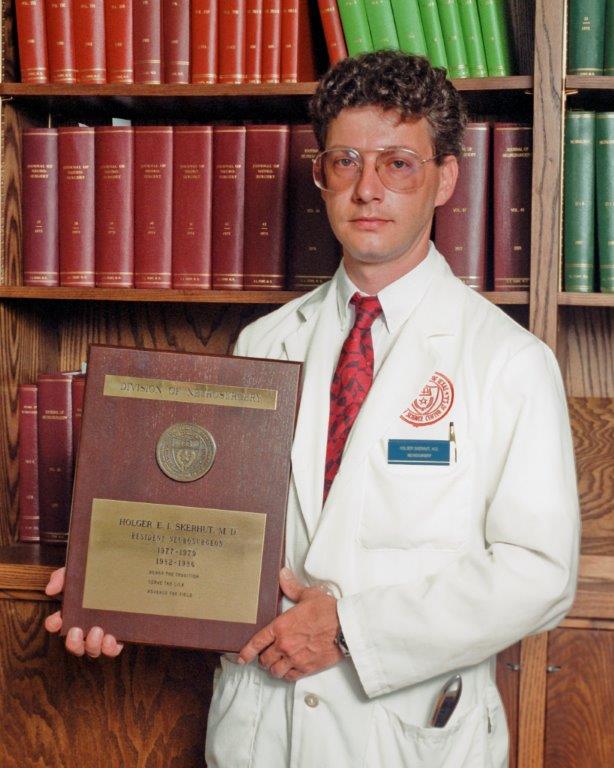 Dr. Holger Skerhut posing with graduation plaque.