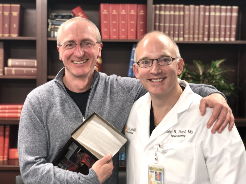 Dr. Floyd and Dr. Bartanusz posed together in the Department of Neurosurgery conference room. Dr. Bartanusz is holding a service award.