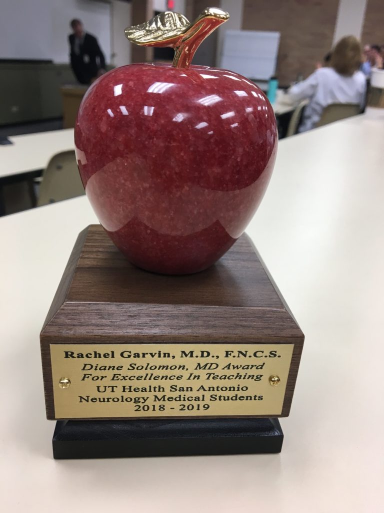 Close up of an award that looks like a red apple carved from stone atop a wooden mantle.
