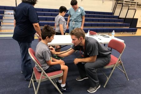 Doctor practicing with stethsascope on child at Special Olympics